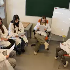 uczniowie w białych fartuchach czekają za zajęcia 